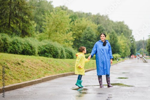 Mom and son in raincoats have fun together in the rain. concept of family vacation and happy childhood. © Serhii
