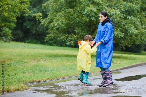Mother and child, boy, playing in the rain, wearing boots and raincoats