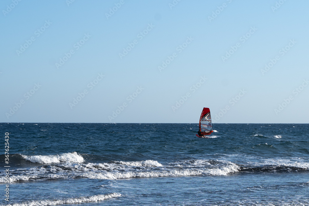 a man on a surfer with a sail rides on the sea