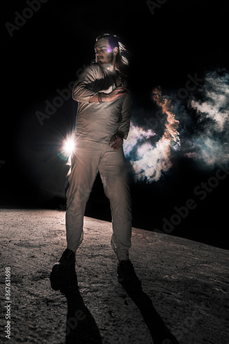 A man in white flax costume and colored smoke. Dark background