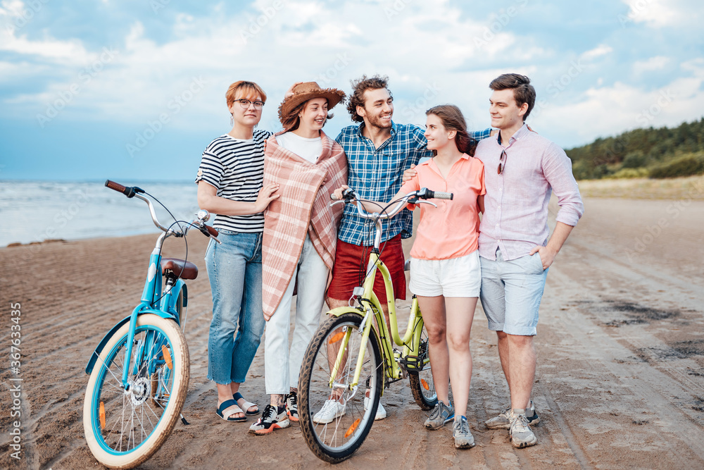 A group of friends are having fun on the beach, smiling, looking at each other A group of friends are having fun on the beach, smiling, looking at each other