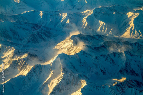 An aerial view of snow covered mountain ranges on a cold winter morning between Red Devil and Nome Alaska