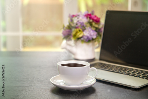 coffee cup and Laptop with blank black screen on wooden  table on morning