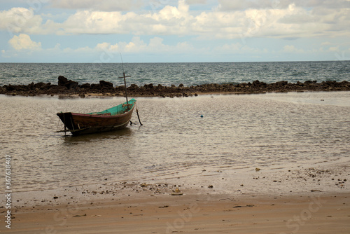 A lone fishing boat at anchor on low tide at the beach