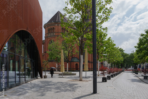 Outdoor exterior view beside rusty copper arch void facade of Wilma Wunder Düsseldorf and background of Johannes Church in Düsseldorf, Germany. photo