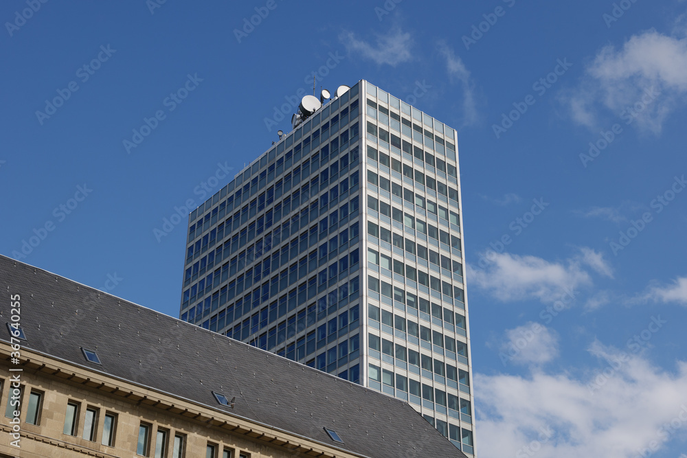 Outdoor sunny and low angle view of Mannesmann Tower, modern architectural style office tower located on riverside Rhine River against blue sky.   
