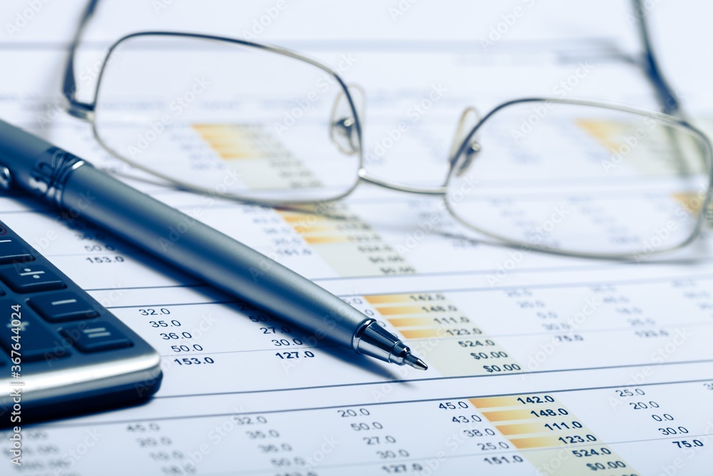 Pen, Eyeglasses and Calculator on Financial Figures Pen, Eyeglasses and Calculator on Financial Figures