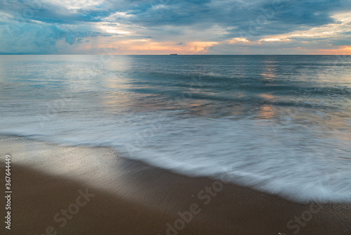 Virginia Beach on a calm cloudy morning, waves crashing on sand