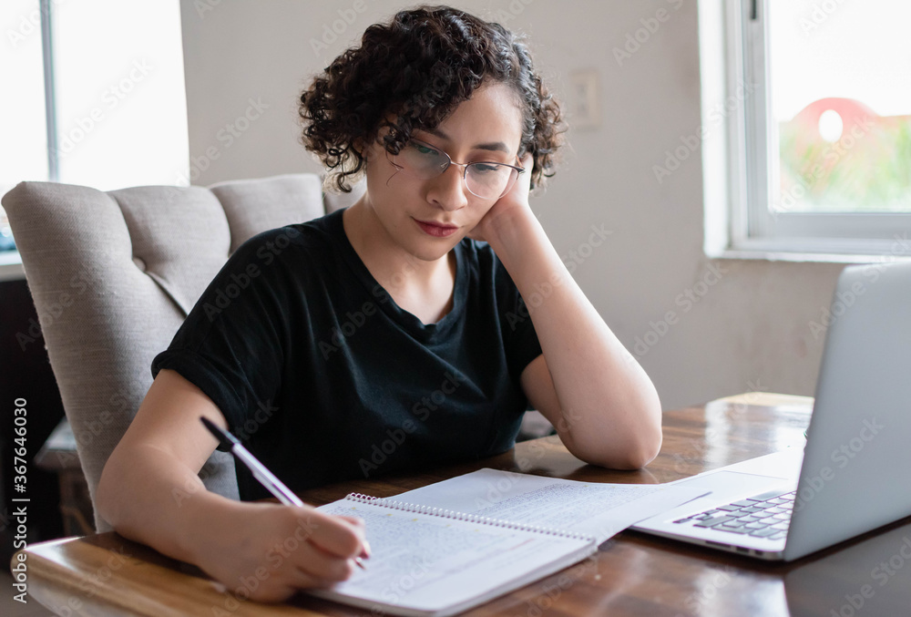 Obraz premium Young woman studying online during quarantine. Working from home.