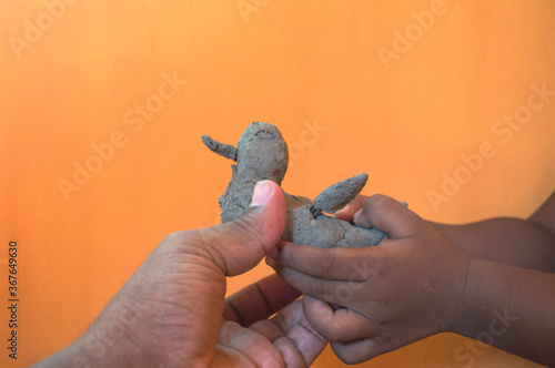 baby's hand taken a clay toy gift from father's hand