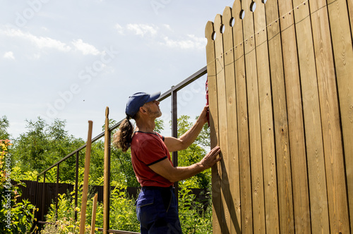 A man builds a wooden fence.