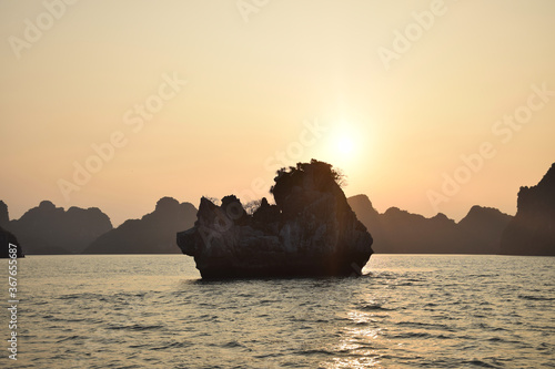 Halong Bay  UNESCO World Heritage  during a cloudless sunset with outlines of the beautiful karst landscape and a tiny island  Vietnam