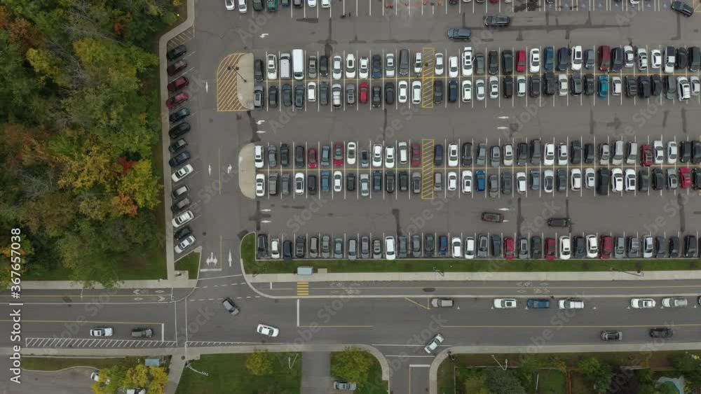 Vertical overhead drone shot of busy parking lot with cars driving within it Vertical overhead drone shot of busy parking lot with cars driving within it