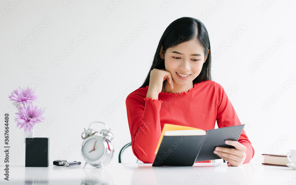 Beautiful asian woman holding and reading a book in the room while sitting. Beautiful asian woman holding and reading a book in the room while sitting.