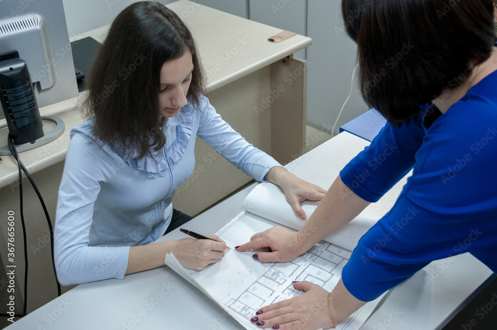 Obraz premium Brunette girl signs drawings in the office