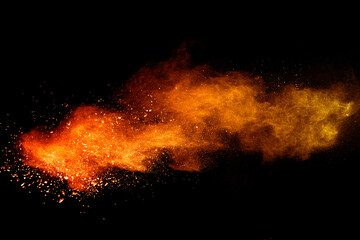 Freeze motion of orange color powder exploding on black background. 
