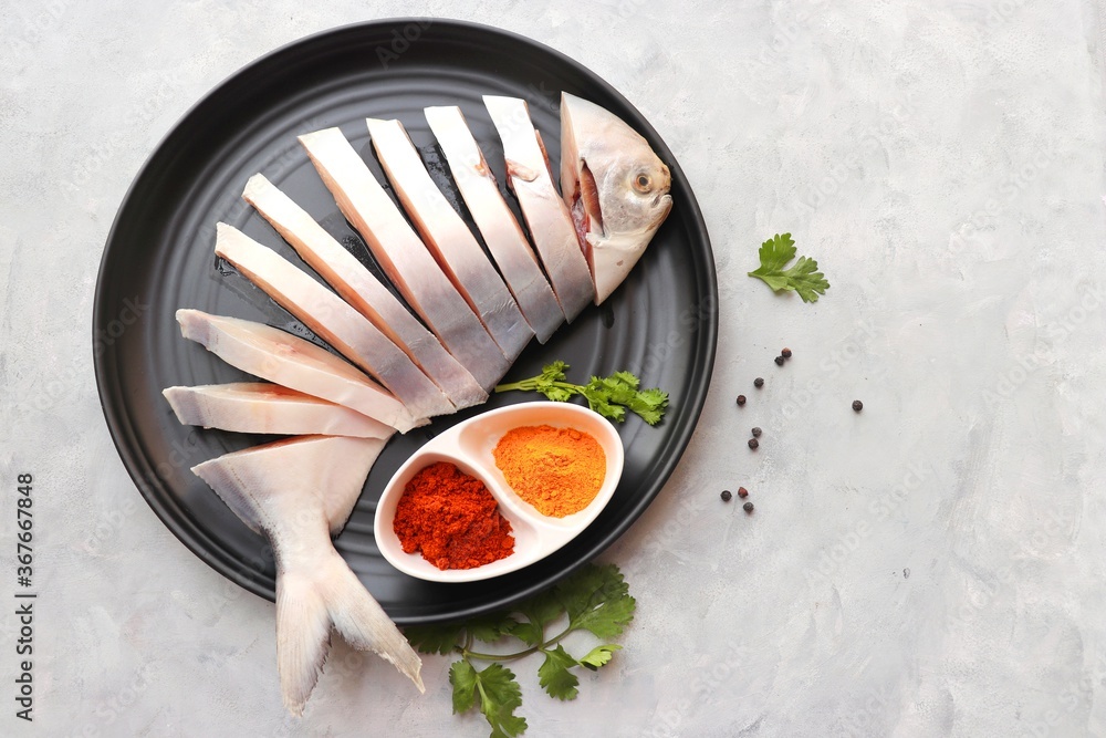 Fototapeta premium Indian fish fry recipe- fresh whole Pomfret fish or butter fish or Poplet cut into slices. cleaned and ready for frying along with spices. ingredients and recipe background with copy space