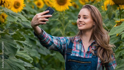 Gorgeous  young  energetic  female taking a picture with herself in the middle of a beautiful sunflower field.