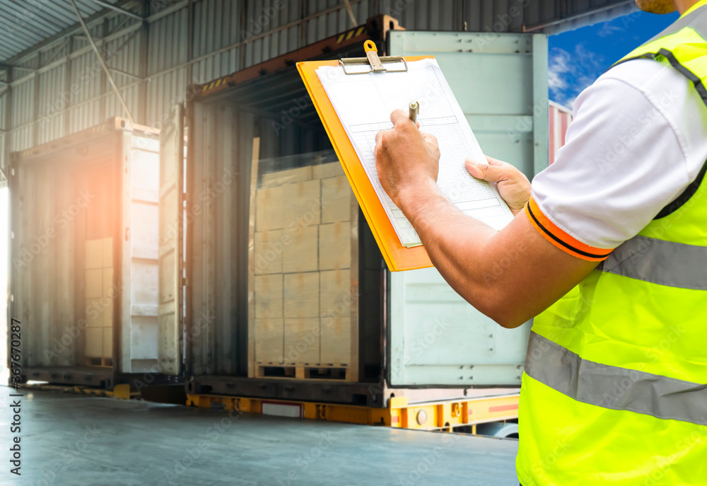 Cargo shipment loading for truck. Worker holding clipboard, his ...