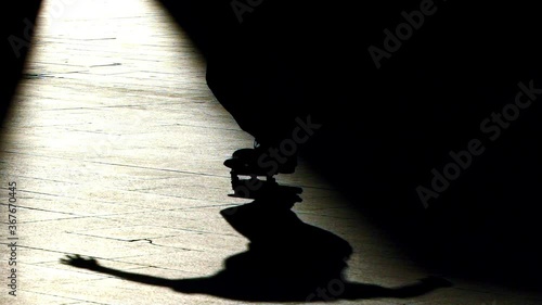 Skateboarder does a trick on a fully backlit silhouette image within a beam light that cuts the image vertically. Nollie bs heelflip the name of the trick photo