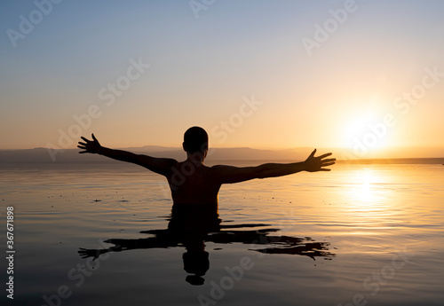 silhouette of a man doing watching the sunset in the dead sea
