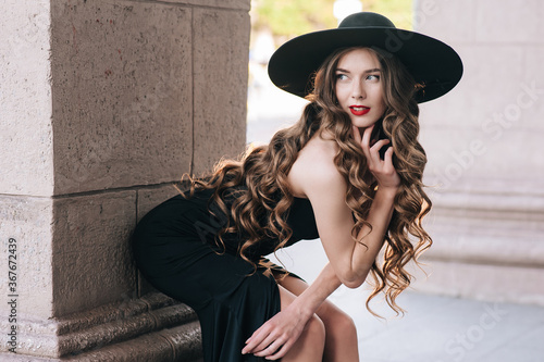 Ukrainian girl in a black dress outdoors in a hat