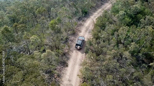 Drone footage of Blue off-road vehicle driving on dirt road in Australian bushland Victoria High Country after fires. photo