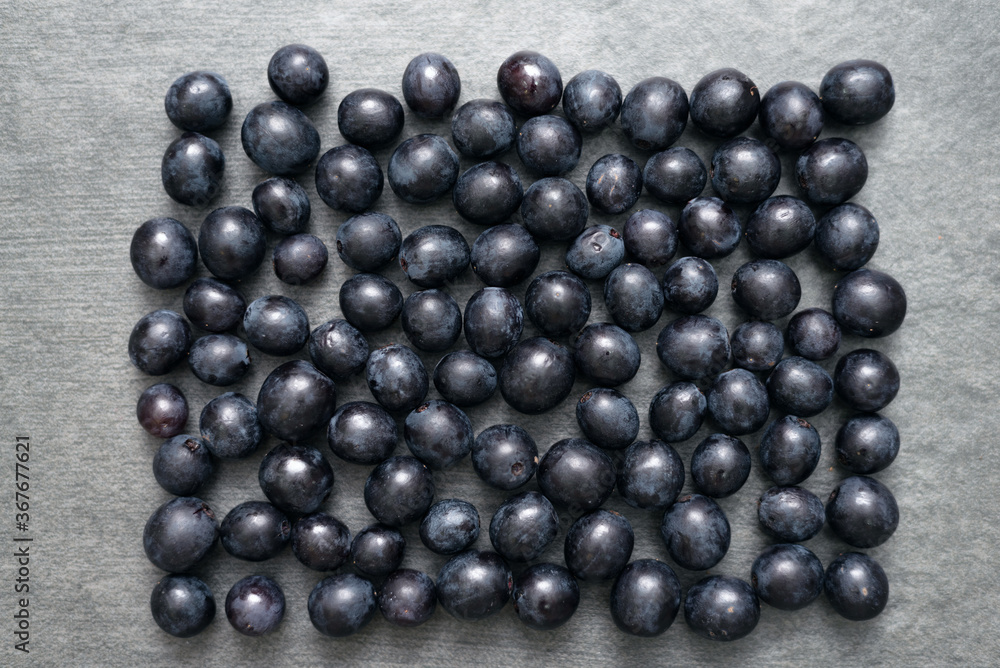 Scattered black grapes on stone surface flat lay background with copy space. Scattered black grapes on stone surface flat lay background with copy space.