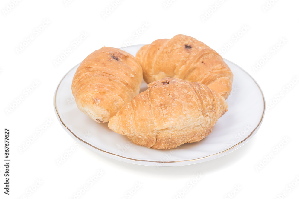 Three small croissants on a white plate on a blue background.