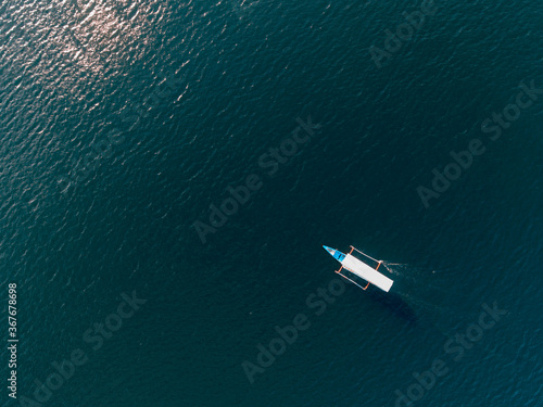 Aerial drone top view photo of small wooden boat in tropical emerald and turquoise clear blue sea © Harry