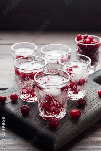 Stacks of vodka and cranberries on a wooden stand and background. Copy of the space. Bar alcoholic beverage tincture.