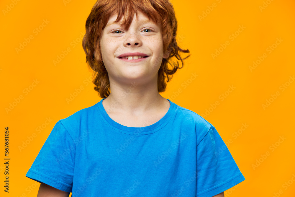 Happy child girl charming smile blue t-shirt yellow background red hair Happy child girl charming smile blue t-shirt yellow background red hair