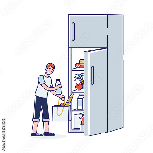 Food in fridge. Boy putting goods after shopping in refrigerator on kitchen