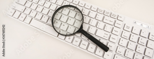 Panoramic view of the writing desk. Top view, flat lay. Business concept. Search for new information. Office desk with keyboard and magnifying glass.