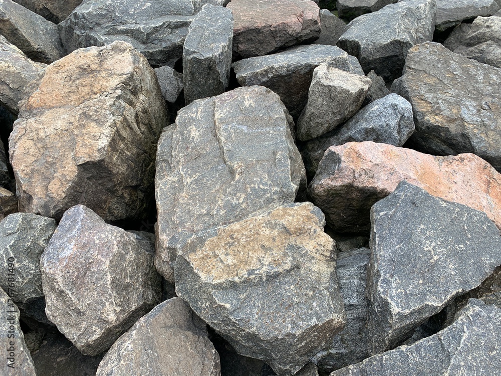 Background texture: many large stones of different shapes. A pile of granite boulders. Concept - stone, hardness, foundation