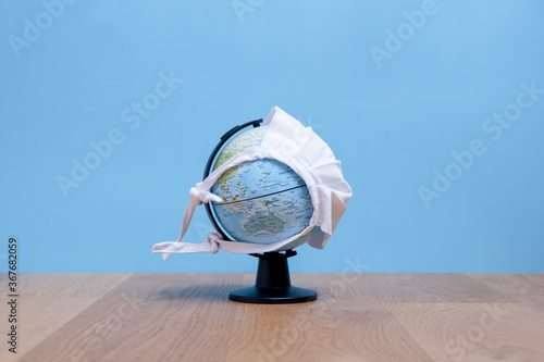 Weltkugel mit weißer Maske mit Sicht auf Australien mit blauem Hintergrund auf einem Holztisch	
 photo