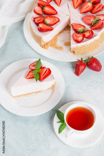 Sweet breakfast, tea and delicious cheesecake with fresh strawberries and mint, homemade recipe without baking, on a blue stone table. Copy space.