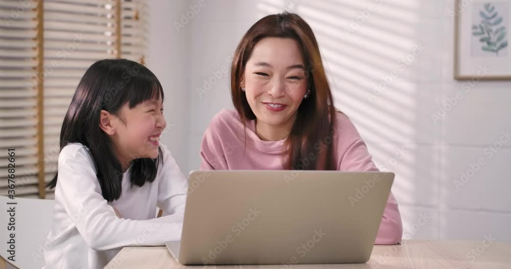 Happy smiling asian mother and cute little kid daughter having fun using laptop online shopping, watch internet videos at home together. Stay home during quarantine of global coronavirus epidemic. Happy smiling asian mother and cute little kid daughter having fun using laptop online shopping, watch internet videos at home together. Stay home during quarantine of global coronavirus epidemic.