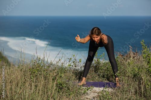 Young woman doing yoga outdoors with amazing back view. Bali. Indonesia.