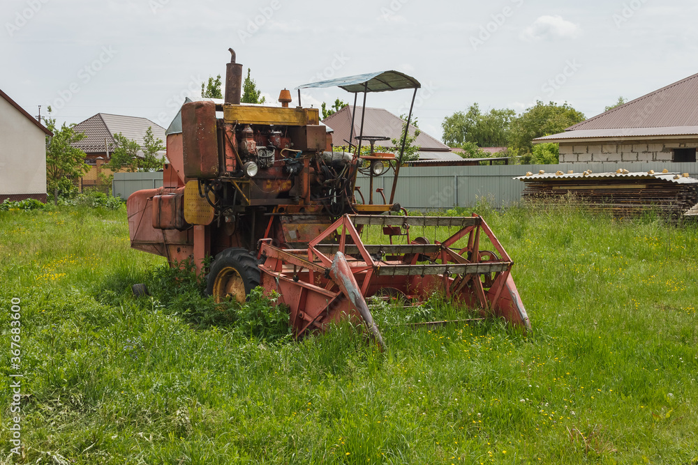 Obraz premium Old combine harvester in the village yard. Old agricultural machinery