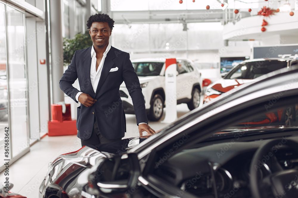 Man buying the car. Businessman in a car salon. Black male in a suit. Man buying the car. Businessman in a car salon. Black male in a suit.