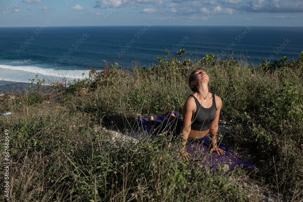 Fototapeta premium Young woman doing yoga outdoors with amazing back view. Bali. Indonesia.