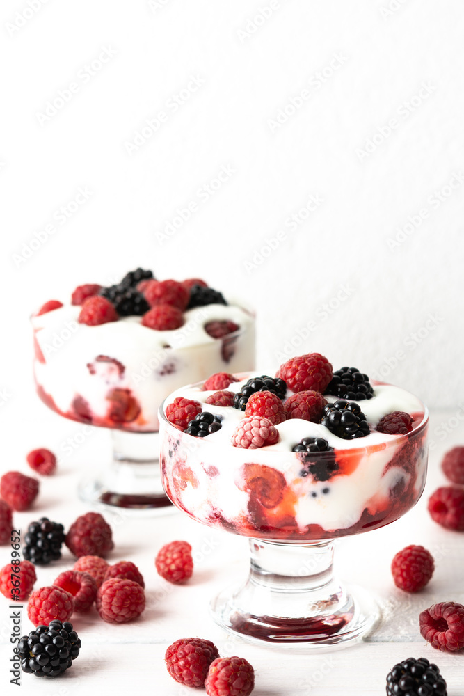 Delicious juicy berries of raspberries and blackberries with yoghurt in a glass form on a white background Delicious juicy berries of raspberries and blackberries with yoghurt in a glass form on a white background
