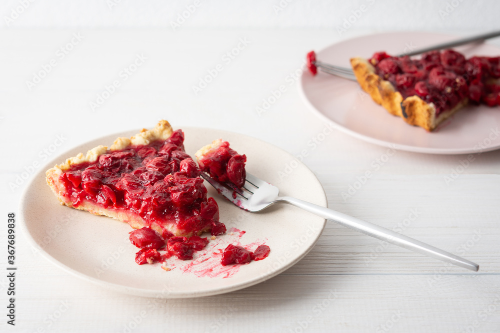Cherry clafoutis on white background, plates with a portion of the pie and spoons Cherry clafoutis on white background, plates with a portion of the pie and spoons