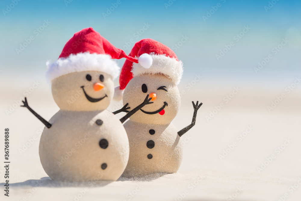 Two Sandy Christmas Snowmen are enjoying Christmas holidays on a beautiful beach, one of them is only in focus