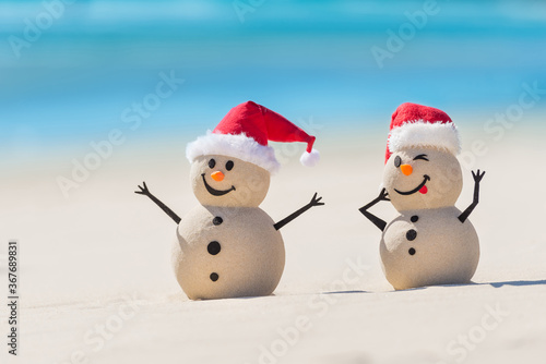 Two Sandy Christmas Snowmen are enjoying Christmas holidays on a beautiful beach  one of them is only in focus