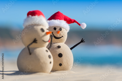 Two Sandy Christmas Snowmen are celebrating Christmas on a beautiful beach  one of them is only in focus