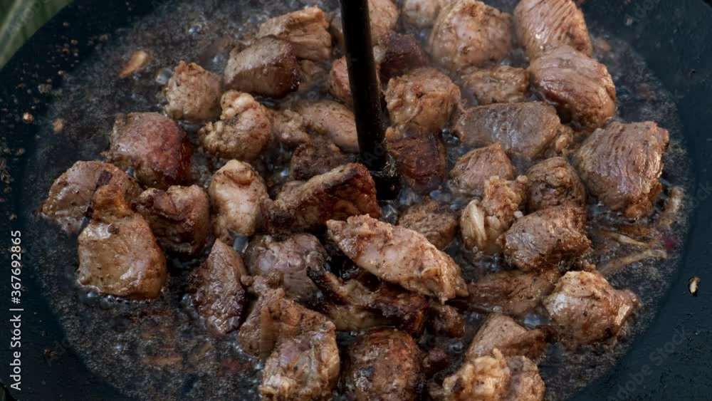 Cooking meat over a fire in a large skillet. Top view. Cooking meat over a fire in a large skillet. Top view.