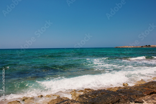 Background of blue sea. Rocky coast of the sea. Mediterranean sea in Cyprus. Nature background. Blue lagoon. Sea shore with summer Sunny day.