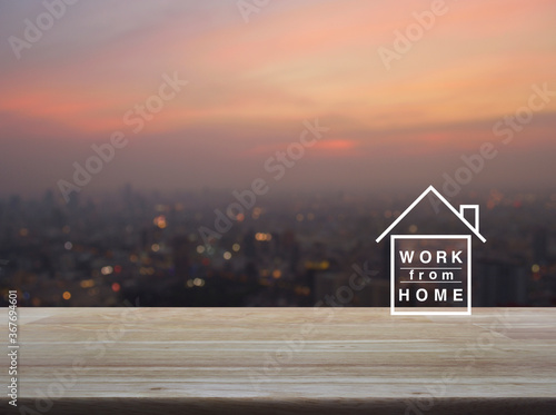 Work from home flat icon on wooden table over blur of cityscape on warm light sundown, Business social distancing online concept